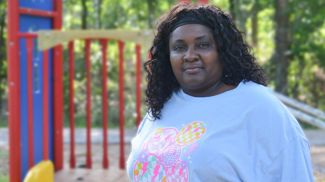 A woman stands outside in front of a playset.